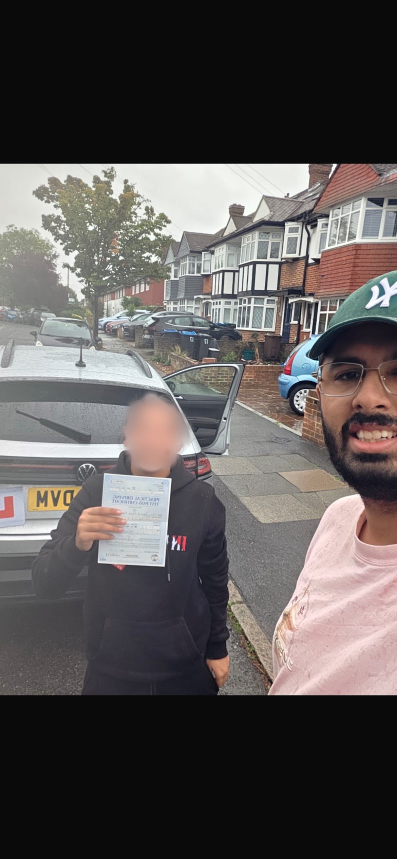 A learner celebrating a test pass with their instructor in a residential street